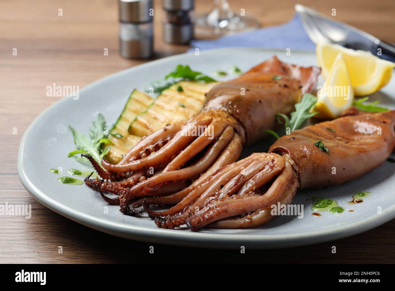 Deliziosi calamari alla griglia serviti su un tavolo di legno, primo piano Foto Stock