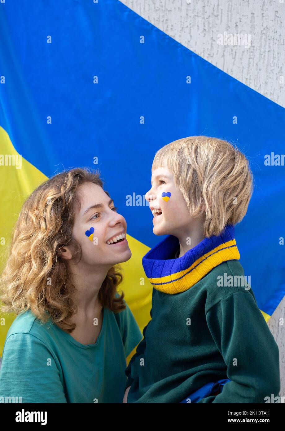 Volti di felice ragazzino e ragazza adulta, fratello e sorella, in profilo, il cuore è disegnato sulla guancia in giallo blu colori della bandiera Ucraina. patriottismo, Foto Stock