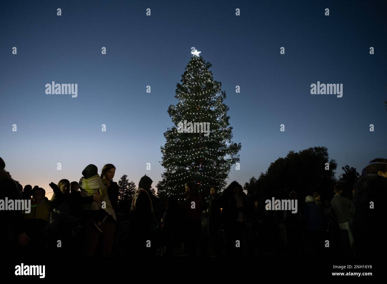 Le famiglie del team Travis si riuniscono intorno a un albero di Natale durante una cerimonia di illuminazione dell'albero di Natale presso la base dell'aeronautica militare Travis, California, 6 dicembre 2022. Le famiglie della Travis AFB si sono riunite per un'illuminazione dell'albero di Natale, per la musica della Band of the Golden West e per una visita di Babbo Natale. (Foto Air Force di Chustine Minoda) Foto Stock