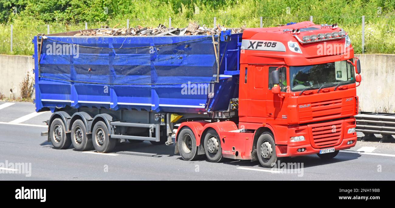 Vista laterale anteriore DAF XF105 rosso hgv motrice autocarro e conducente traino rimorchio ribaltabile articolato blu caricato con rottami guida su autostrada M25 UK Foto Stock