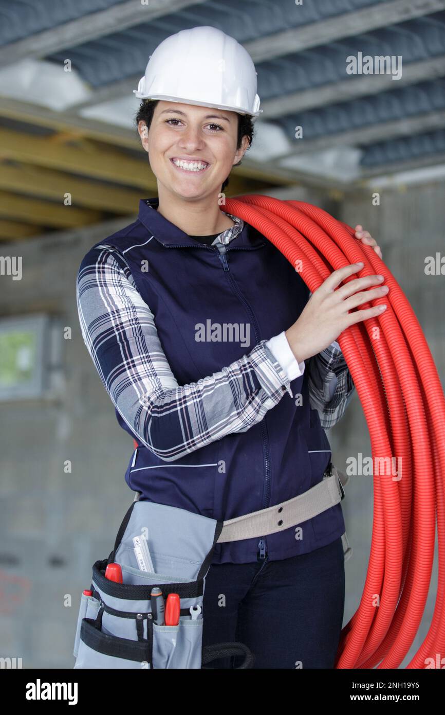 idraulico femmina che porta una bobina di tubo rosso Foto Stock
