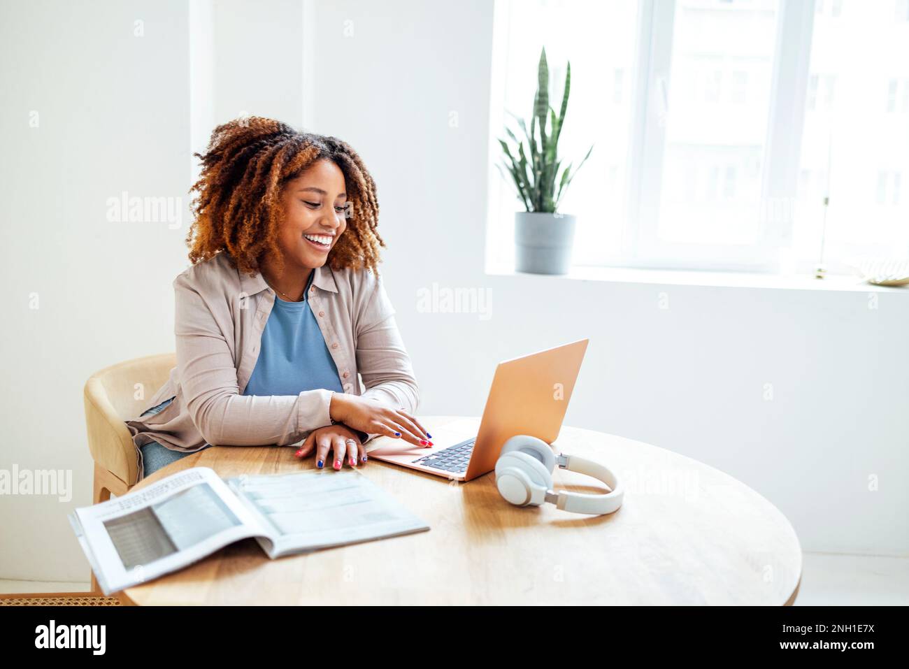 Una giovane afroamericana sta lavorando su un computer portatile. Una studentessa felice sta guardando lo schermo del computer e guardando il webinar o facendo videochat da noi Foto Stock