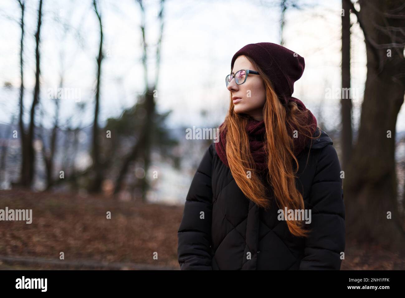 donna dai capelli rossi in un cappello e giacca in giù nel mezzo del parco Foto Stock