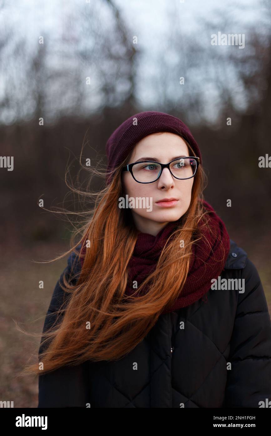 donna dai capelli rossi in un cappello e giacca in giù nel mezzo del parco Foto Stock