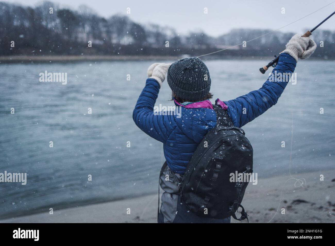 Donna pescatore casting canna da mosca in tempesta di neve Foto Stock