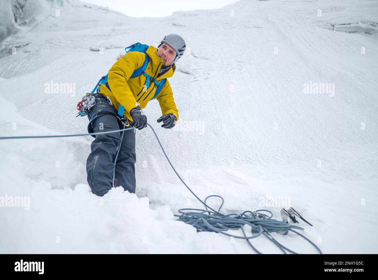 Maschio che si arrampica tirando la corda per il suo compagno di squadra Foto Stock