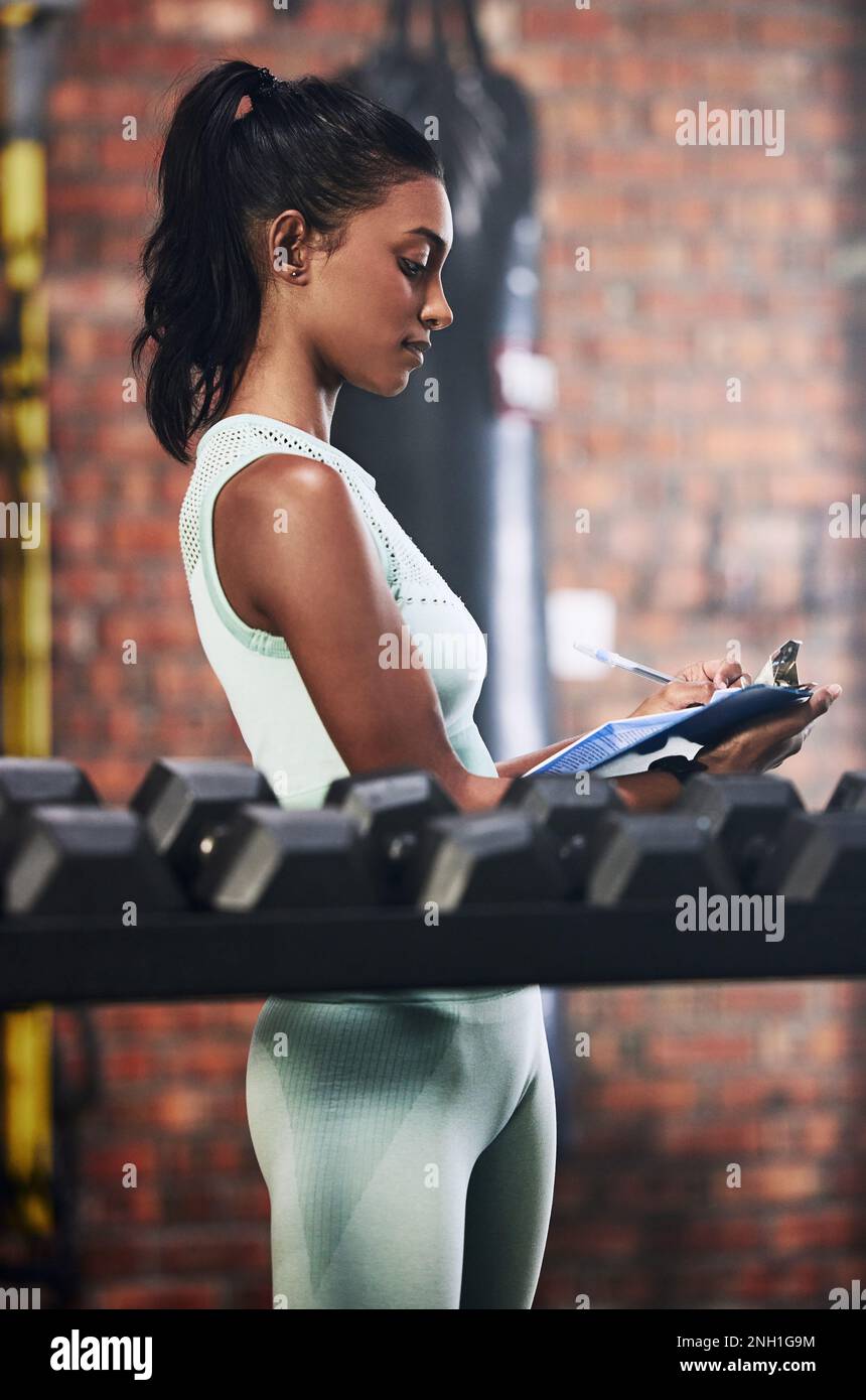La palestra locale ha molto da offrire. una giovane donna che fa l'inventario mentre lavora in una palestra. Foto Stock