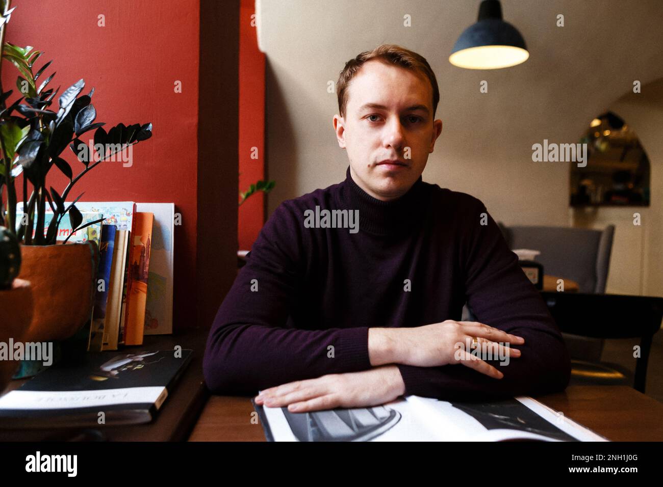 il giovane si siede da solo ad un tavolo con riviste Foto Stock