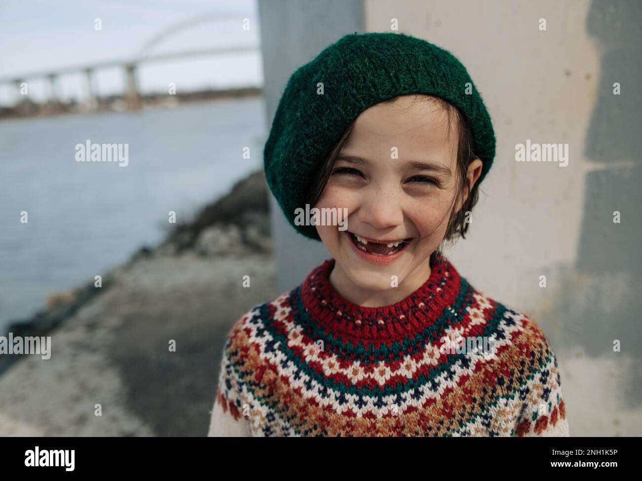 ragazza sorridente in cappello e maglione sotto un ponte perso i denti anteriori Foto Stock