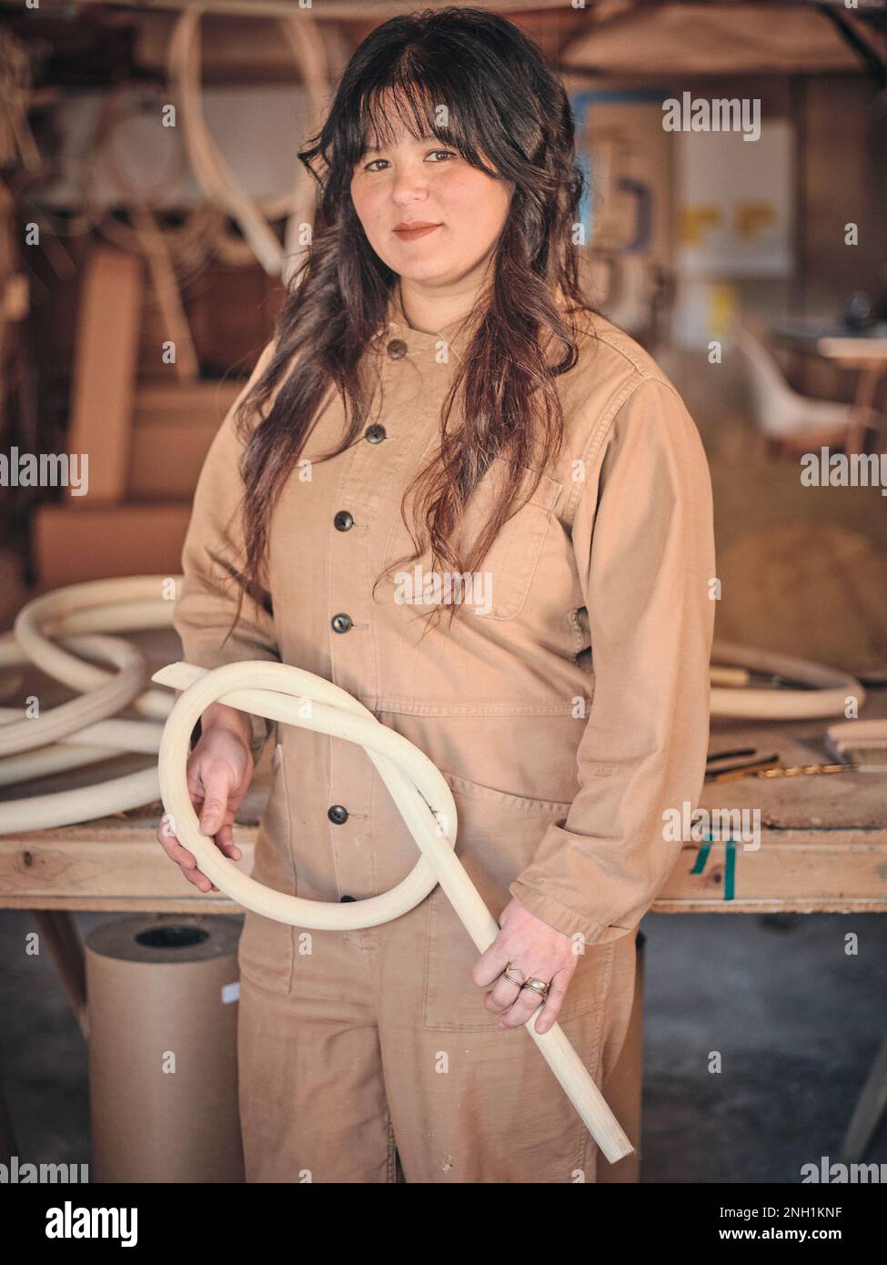 Un'artista femminile nel suo studio lavora con una delle sue sculture in legno Foto Stock