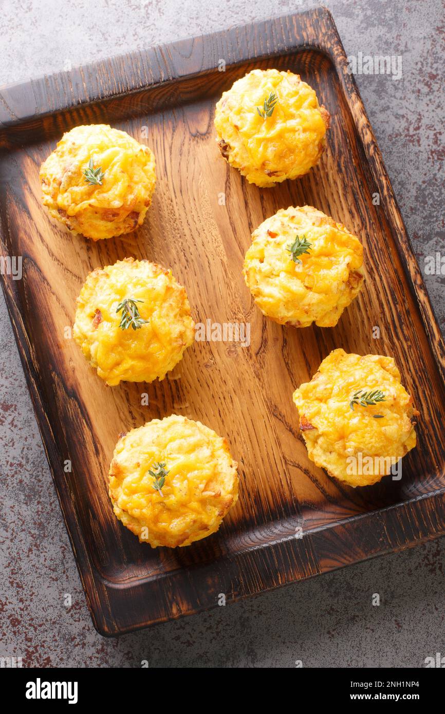 Deliziosi muffin di patate con pancetta e formaggio cheddar primo piano su un asse di legno sul tavolo. Vista verticale dall'alto Foto Stock