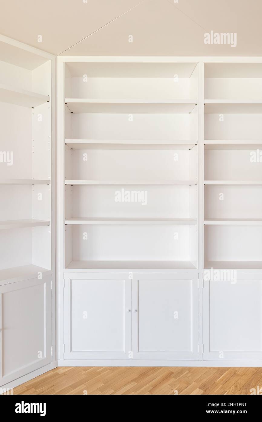 Guardaroba bianchi da pavimento a soffitto lungo le pareti della camera. Molti scaffali per vari articoli interni, libri. Da sotto armadietti con porte per Foto Stock