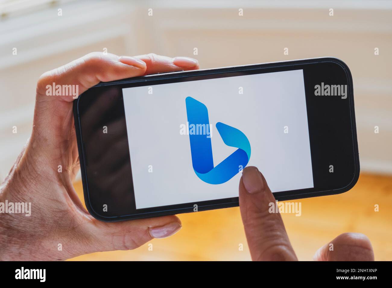 La persona tiene il telefono cellulare che mostra il nuovo logo del motore di ricerca Microsoft ChatGPT OpenAI Bing sullo schermo Foto Stock