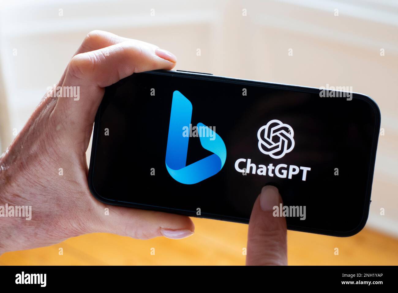 La persona tiene il telefono cellulare che mostra il nuovo logo del motore di ricerca Microsoft ChatGPT OpenAI Bing sullo schermo Foto Stock