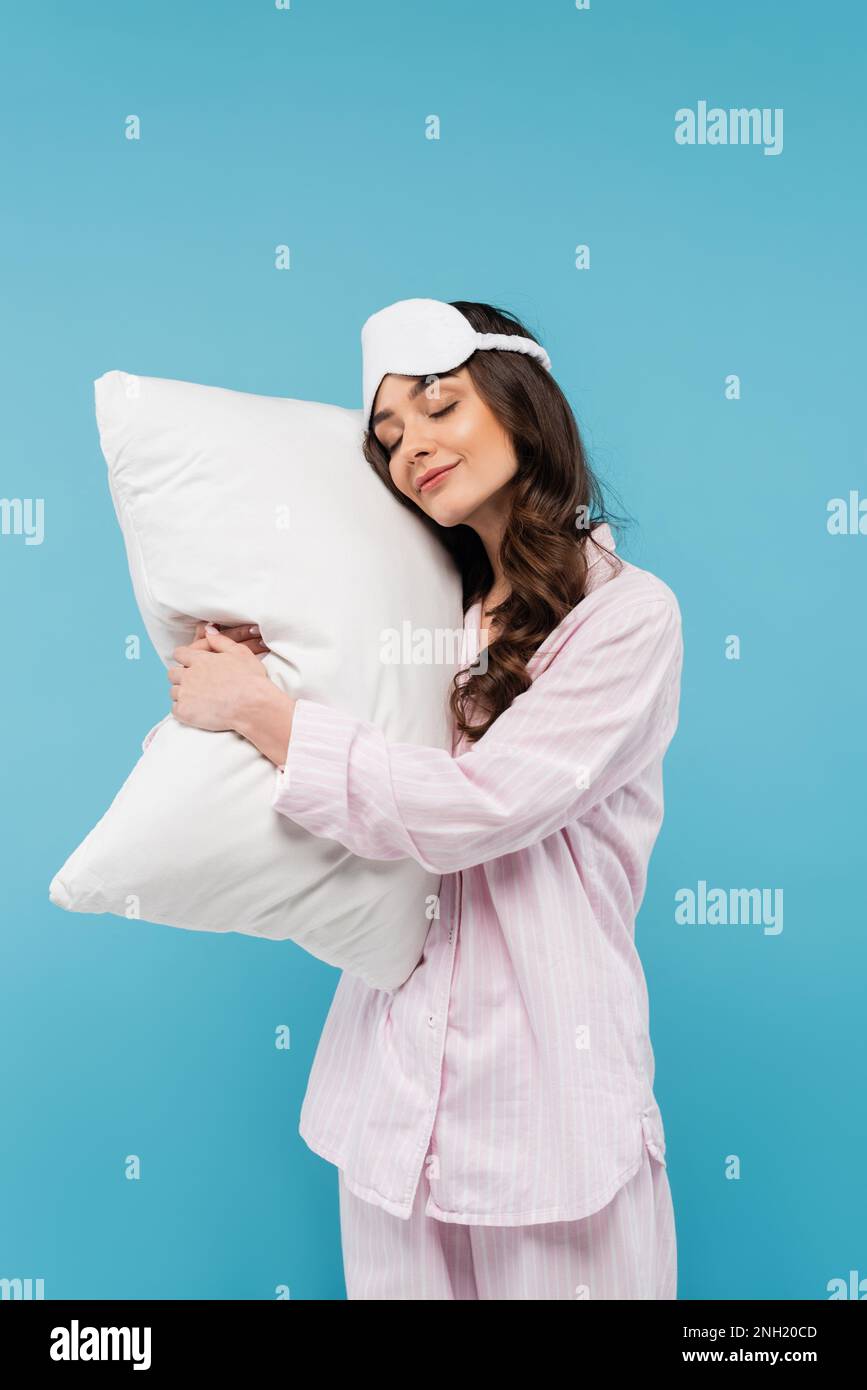 giovane donna in pigiama e maschera notte che dorme su cuscino bianco isolato su blu, immagine stock Foto Stock