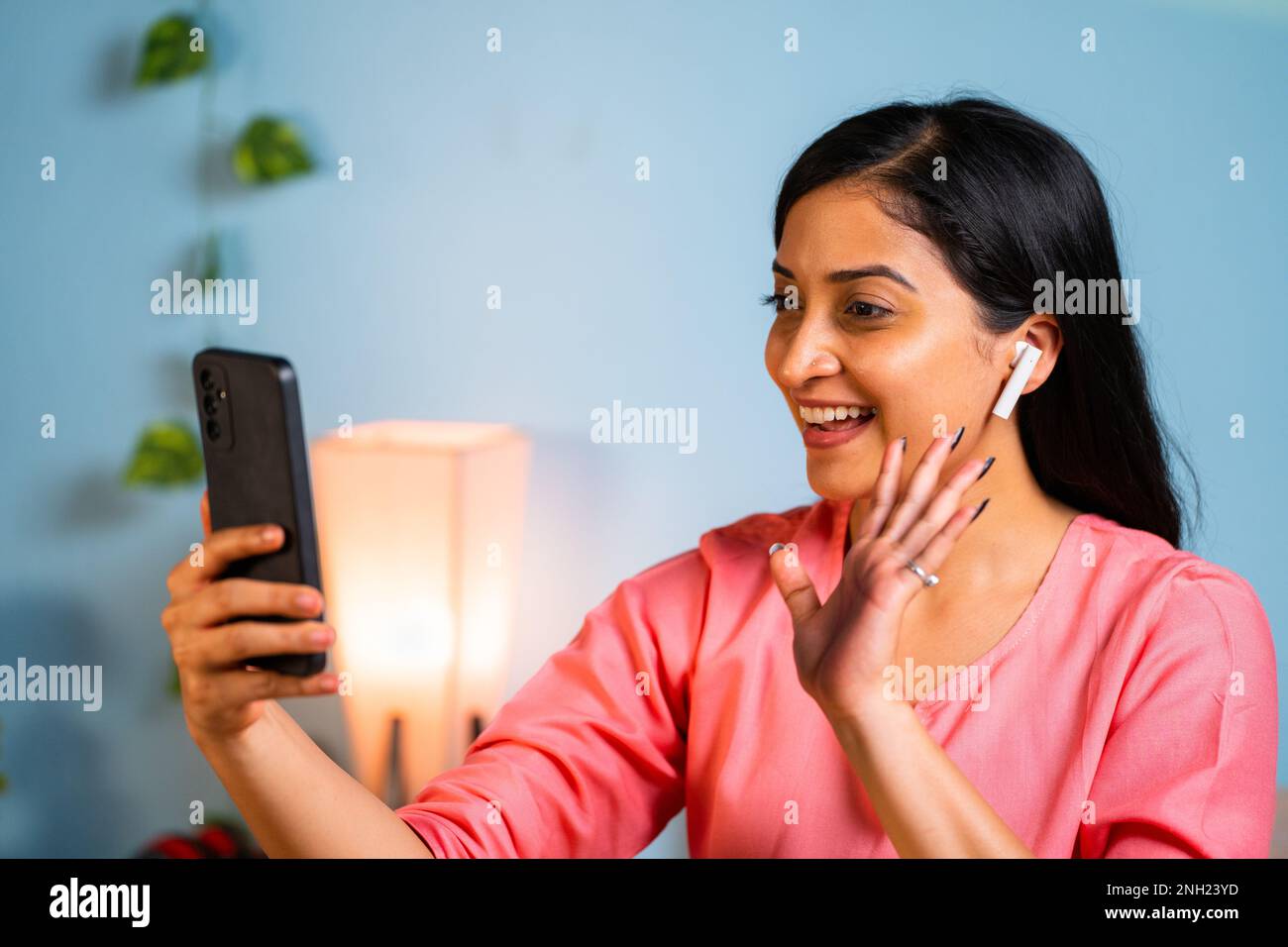 Ragazza felice con auricolari che parlano in videochiamata sul telefono cellulare a casa - concetto di tecnologia, connessione e comunicazione. Foto Stock