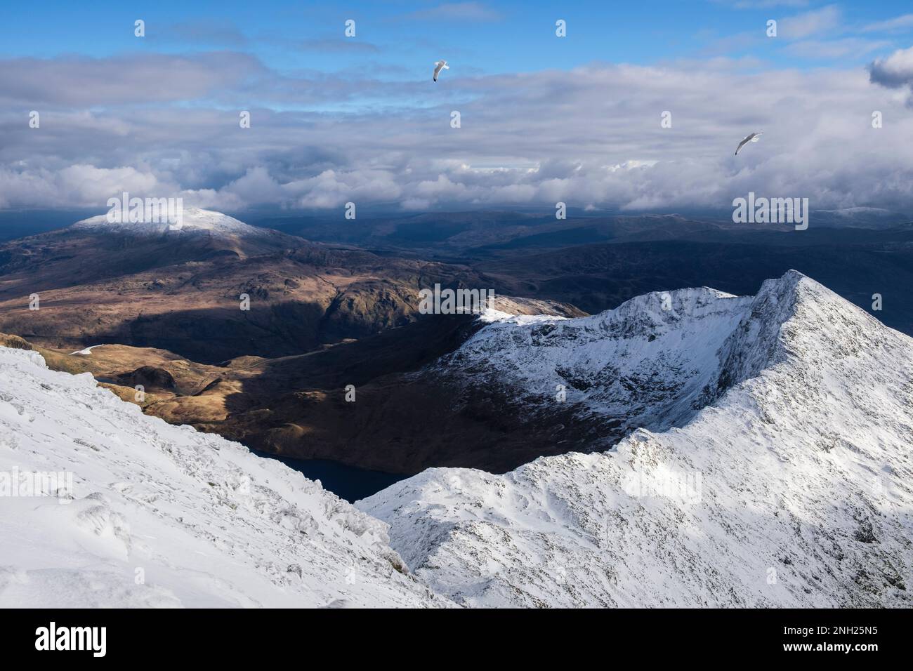 Vista a Y Lliwedd a ferro di cavallo di Snowdon dalla cresta sud nella neve d'inverno nelle montagne del Parco Nazionale di Snowdonia. Gwynedd, Galles del Nord, Regno Unito, Gran Bretagna Foto Stock