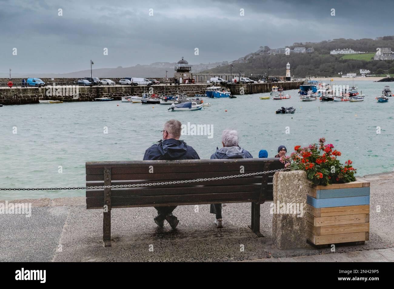 Meteo nel Regno Unito. I visitatori seduti su una panchina in una giornata piovosa e fredda nella storica cittadina costiera di St Ives, in Cornovaglia, in Inghilterra, nel Regno Unito. Foto Stock