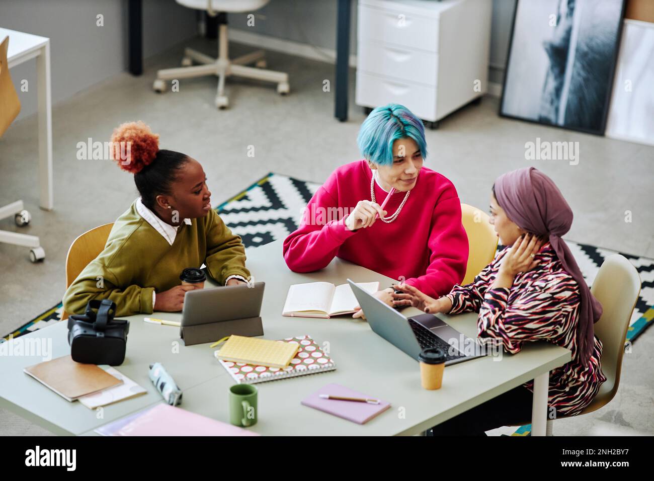 Gruppo vario di giovani creativi che discutono il progetto durante la riunione in ufficio fuoco sull'uomo asiatico con i capelli colorati Foto Stock