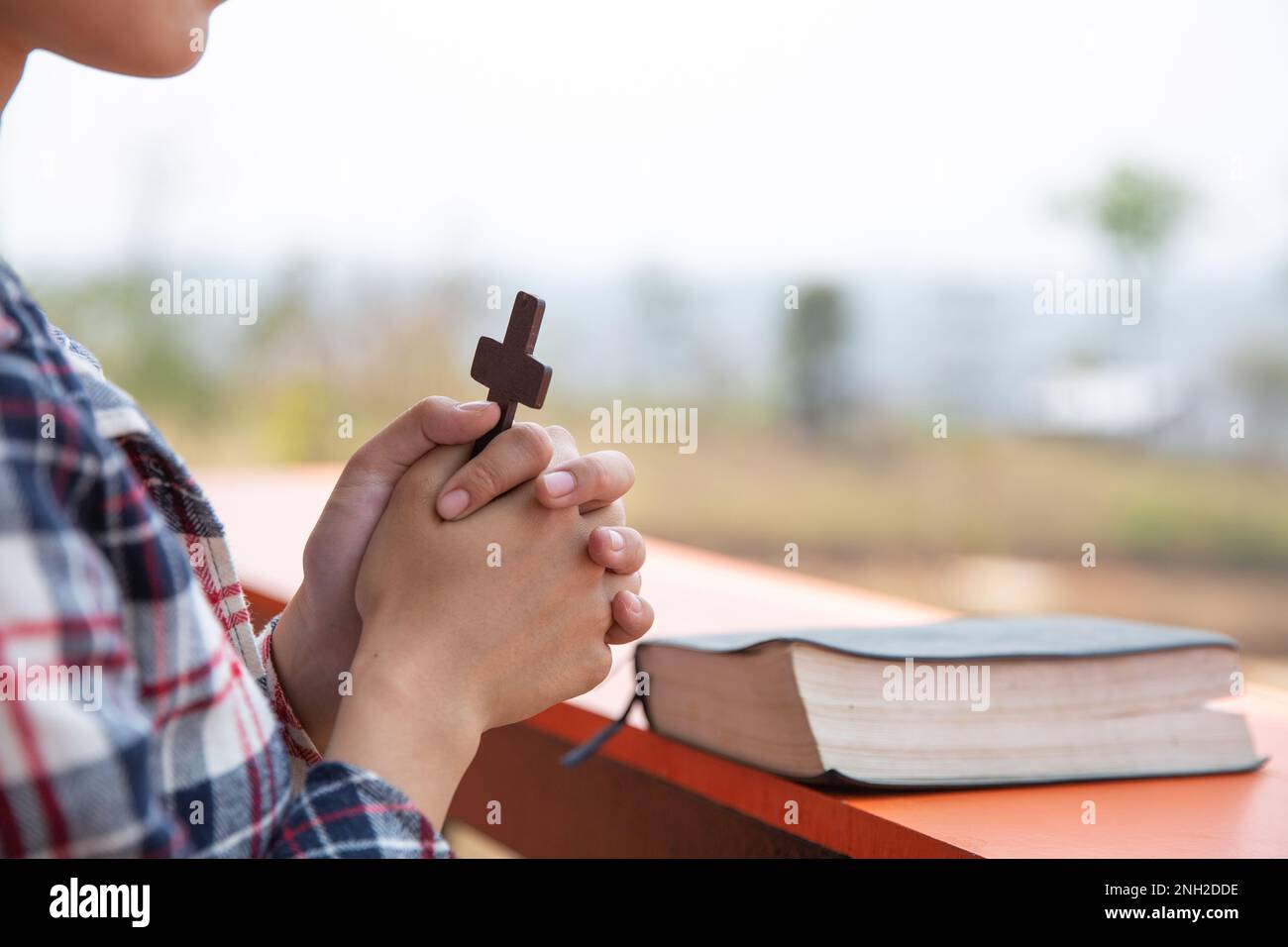 Giovani donne che pregano mani con croce di legno e la Sacra Bibbia. Concetto di religione Foto Stock