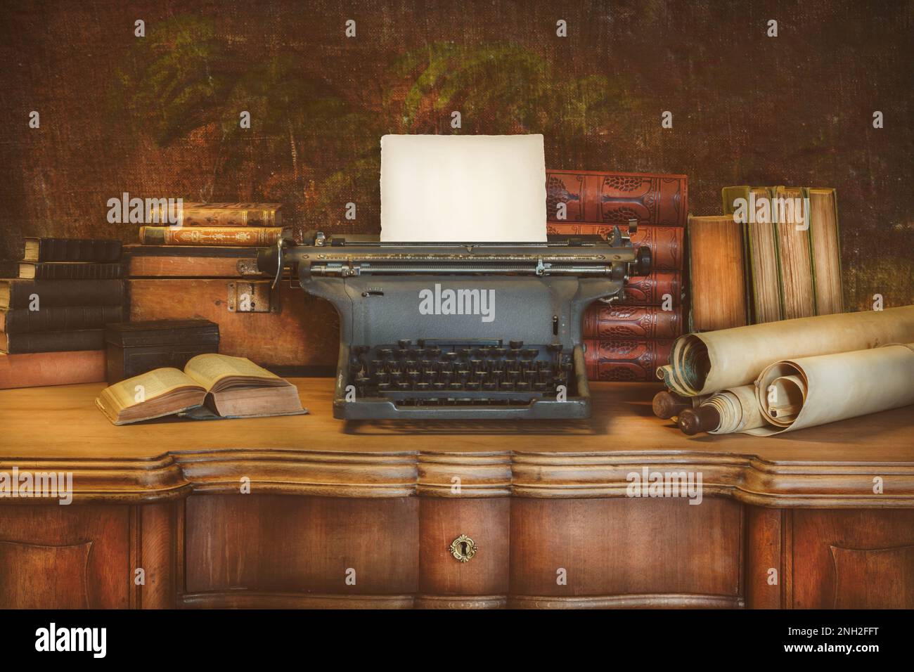 Vecchia scrivania in legno con macchina da scrivere d'epoca contenente un foglio di carta vuoto e antichi libri e mappe Foto Stock