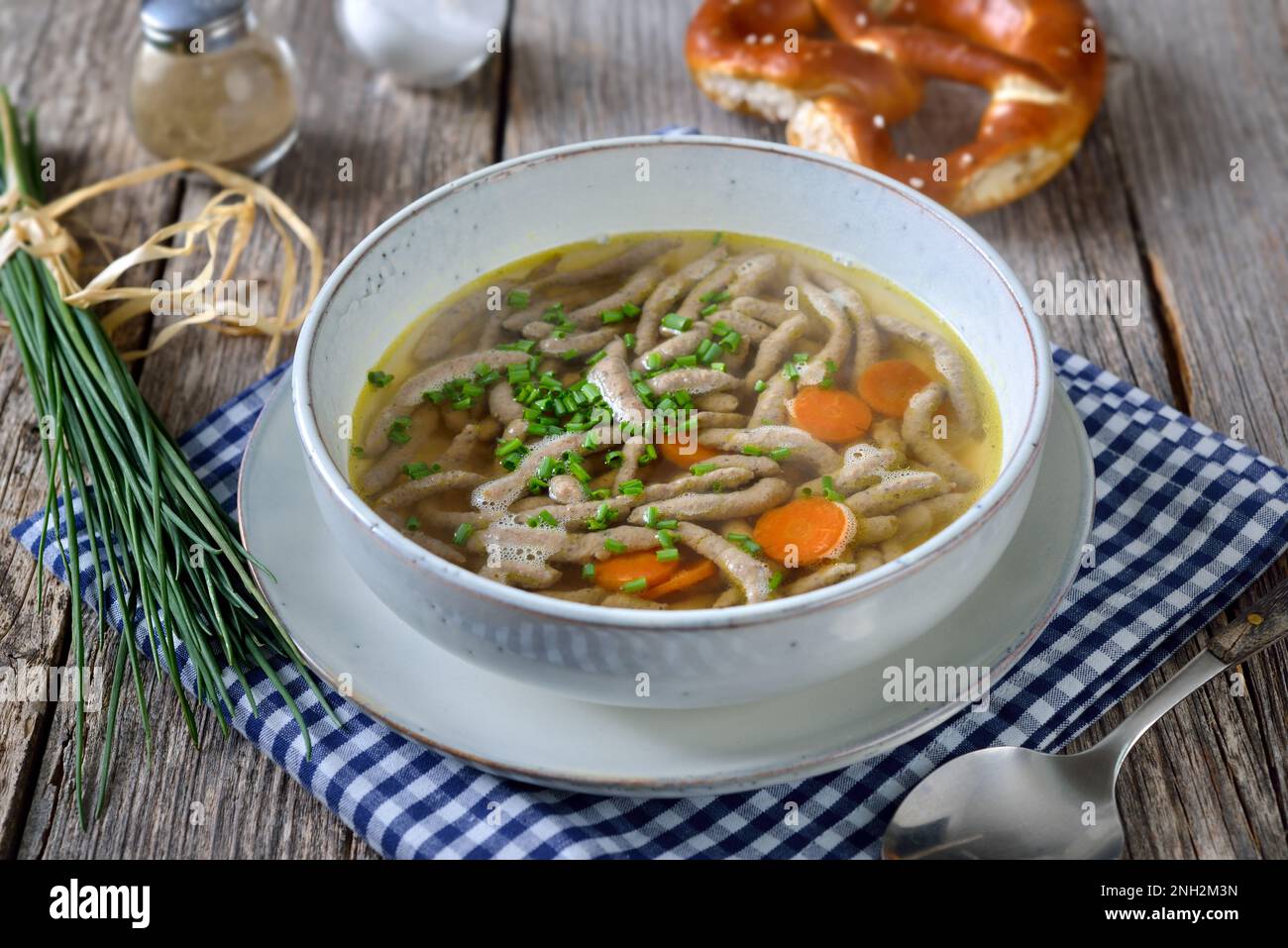 Piatto bavarese, svevo e austriaco - spaetzle di fegato in una zuppa di manzo servita con un pretzel croccante Foto Stock