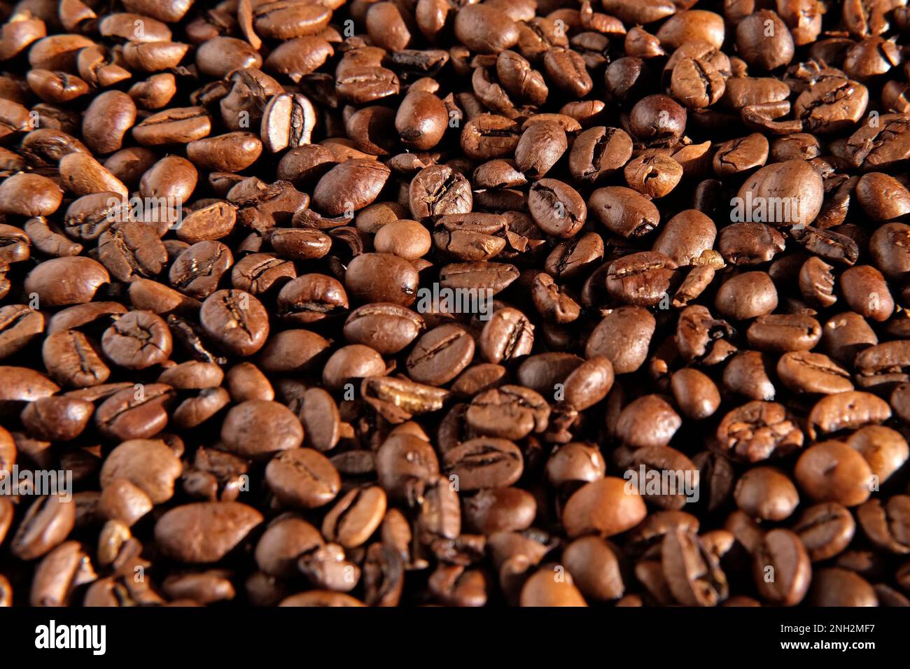 Fondo in grani di caffè. La consistenza dei chicchi di caffè si avvicina. Il caffè tostato marrone scuro sta girando. Abbondanza. Concetto per la pubblicità dei prodotti del caffè. S Foto Stock