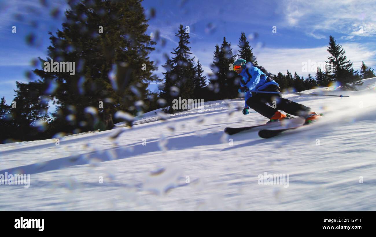 Sciatore professionista sulle piste delle alpi Svizzere e sciando la neve alla macchina fotografica. Gocce d'acqua visibili. Foto Stock