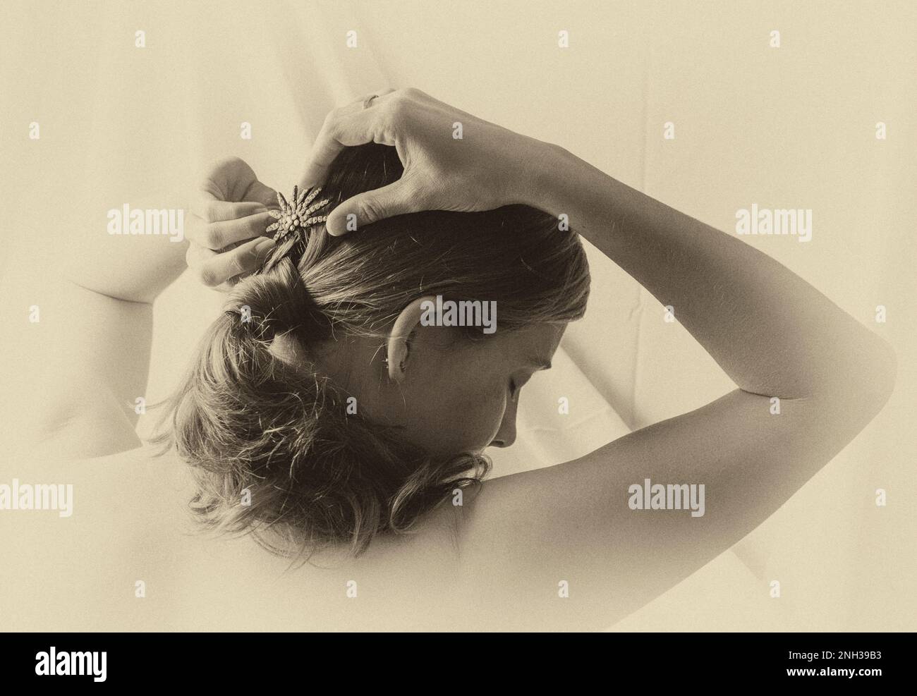 Vista posteriore della giovane donna che fissa i capelli. Foto Stock