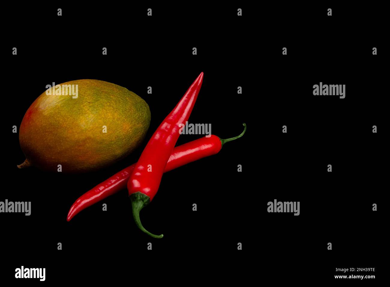 Mango interi e peperoncino su fondo nero. Foto Stock