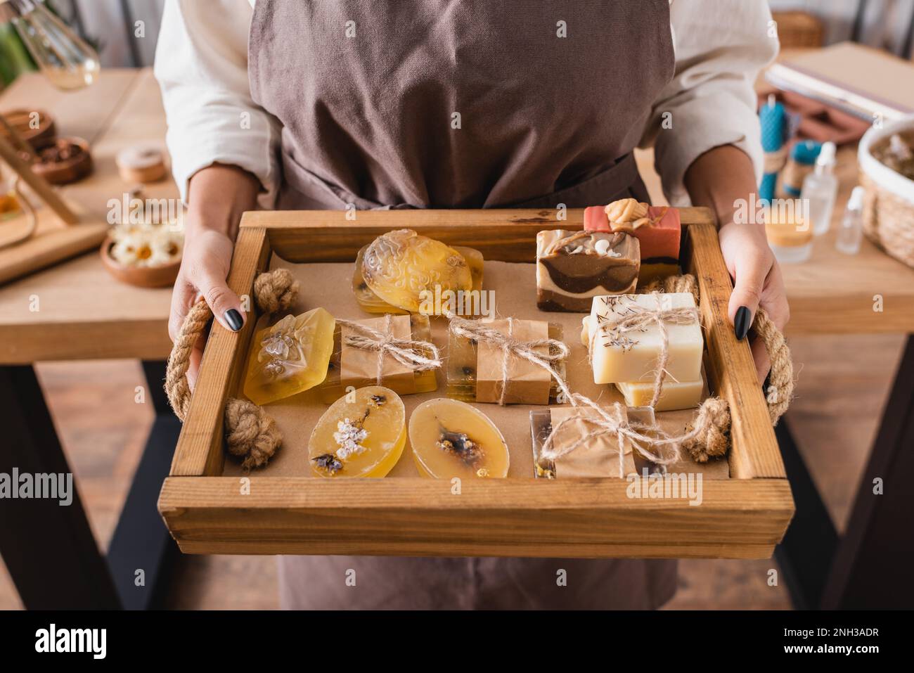 vassoio di legno con assortimento di sapone fatto a mano in mani di taglio afro-americano artigianale, immagine stock Foto Stock