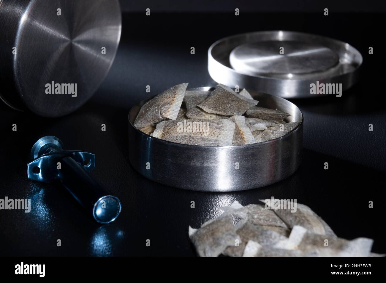 Helsinki / Finlandia - 20 FEBBRAIO 2023 - chiusura di un tino svedese metallico con bustine di snus bianche. Un portatore di snus sciolto blu nel fo Foto Stock