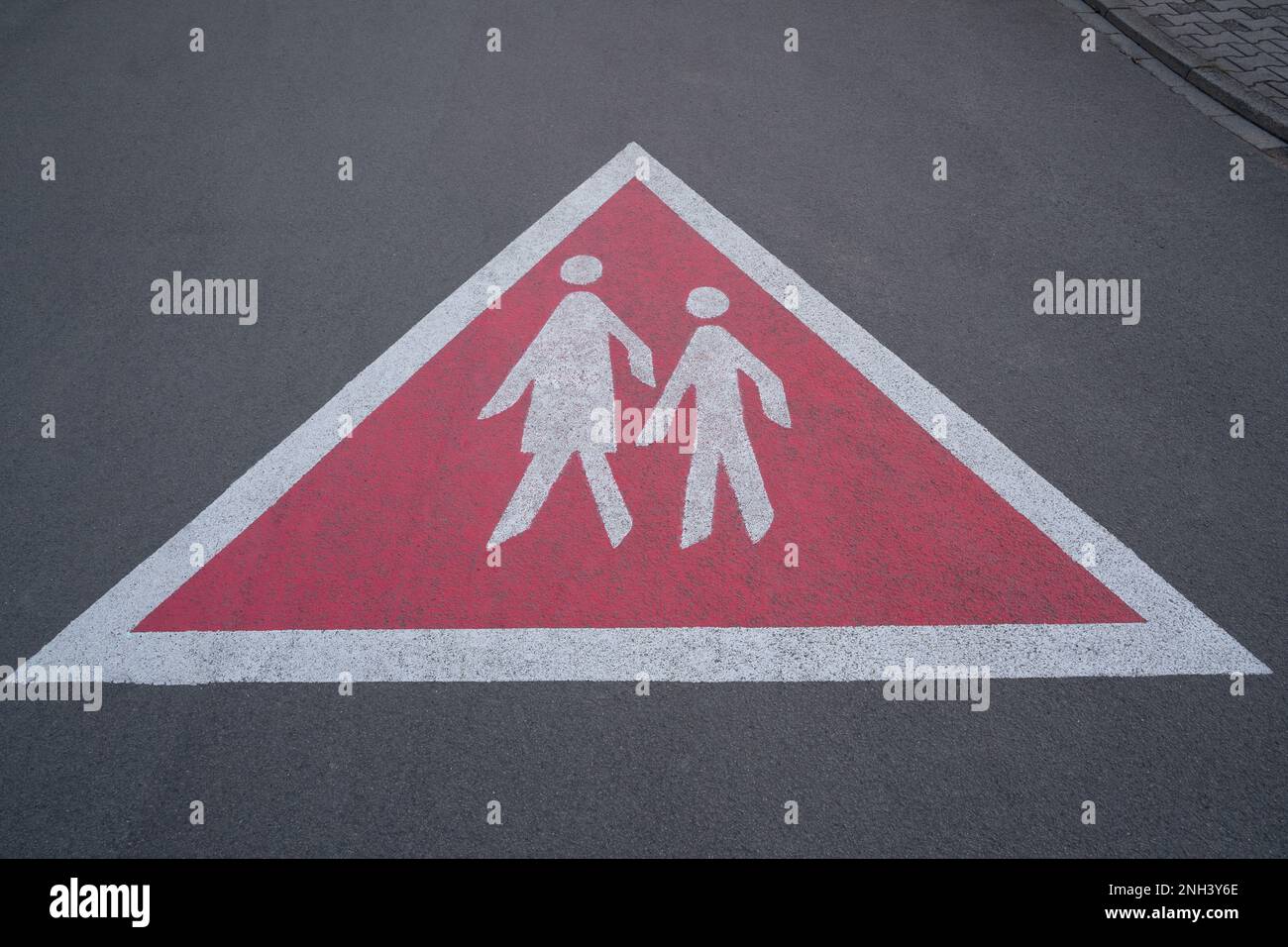 Cartello di segnalazione triangolare sulla strada asfaltata che mostra pedoni a piedi. In modo che i conducenti guidino con attenzione e guardino fuori i pedoni. Foto Stock