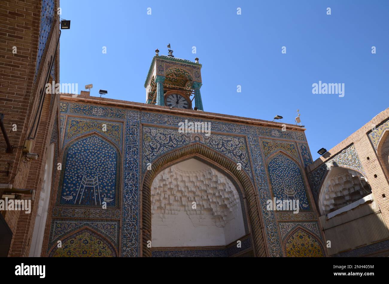 Porta e torre dell'orologio di una moschea colorata a Kerman, Iran Foto Stock