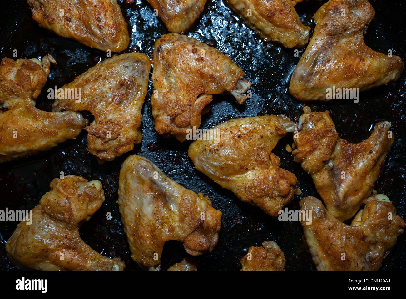 Vista dall'alto delle ali di pollo croccanti su una teglia da forno nera Foto Stock