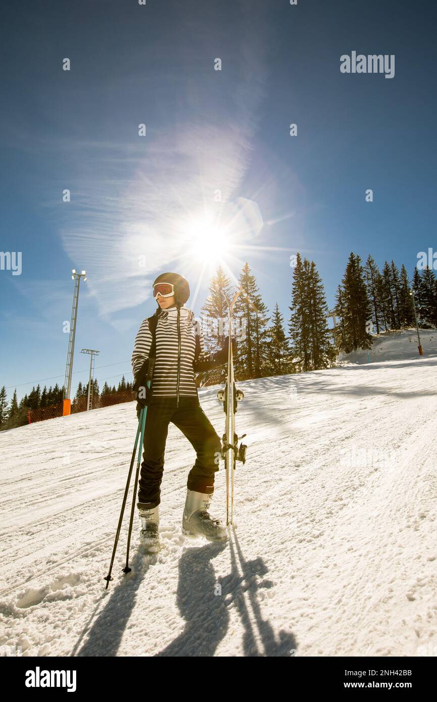 Una sola giovane donna gode di una soleggiata giornata invernale di sci,  vestita con attrezzatura da neve completa con scarponi da sci e occhiali da  sole Foto stock - Alamy