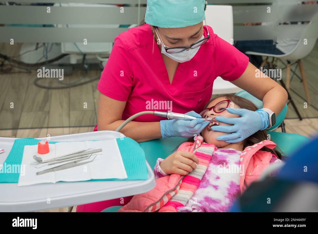 Dentista che pulisce i denti di una ragazza nel suo studio dentale Foto Stock