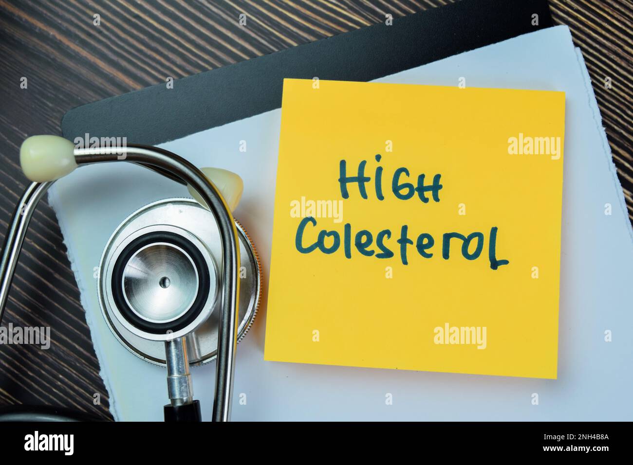 Concetto di Alto Colesterolo scrivere su note appiccicose isolato su tavola di legno. Foto Stock