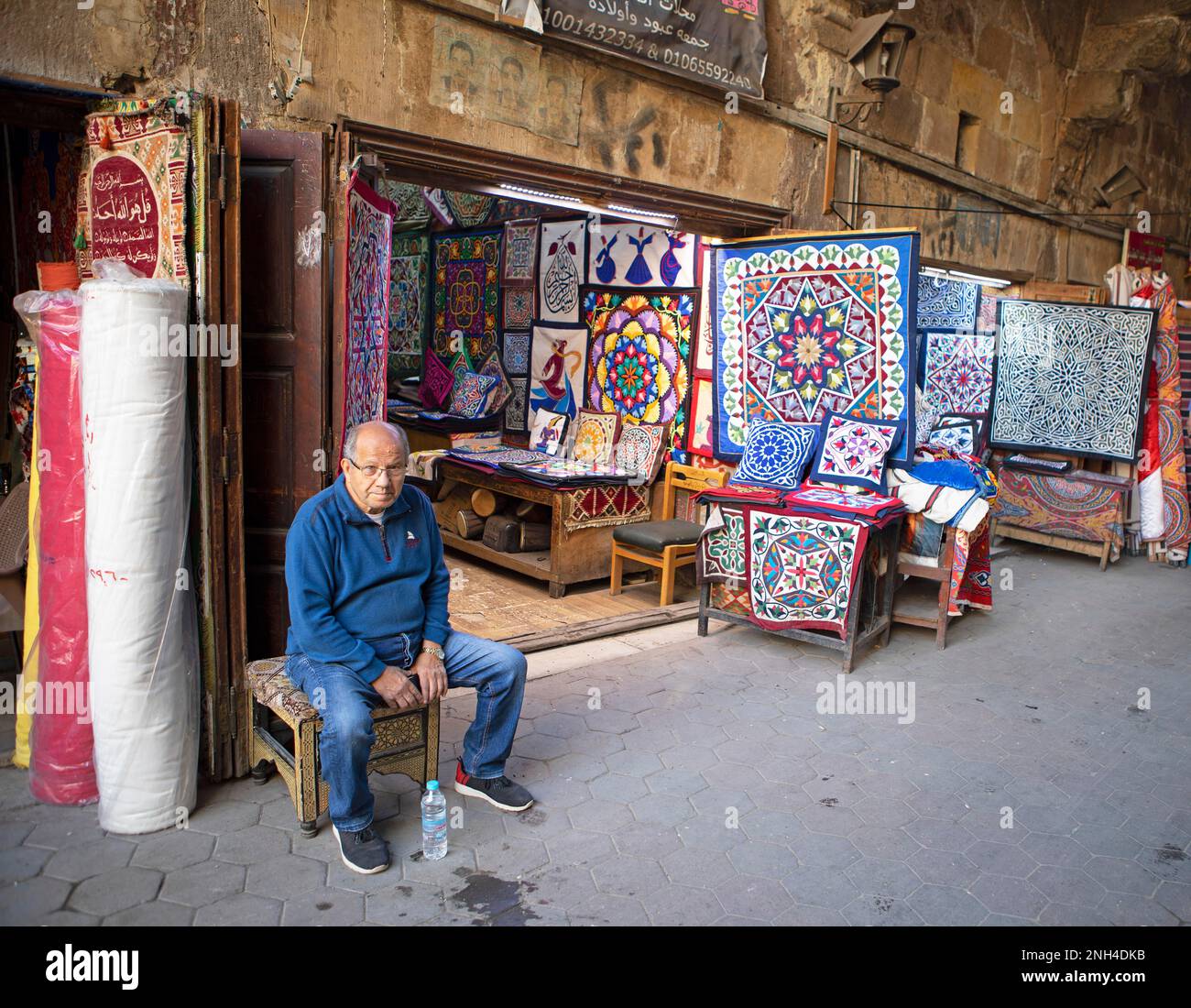 Uomo egiziano seduto in un negozio paisley, bazar tentmaking, Città Vecchia, il Cairo, Egitto Foto Stock