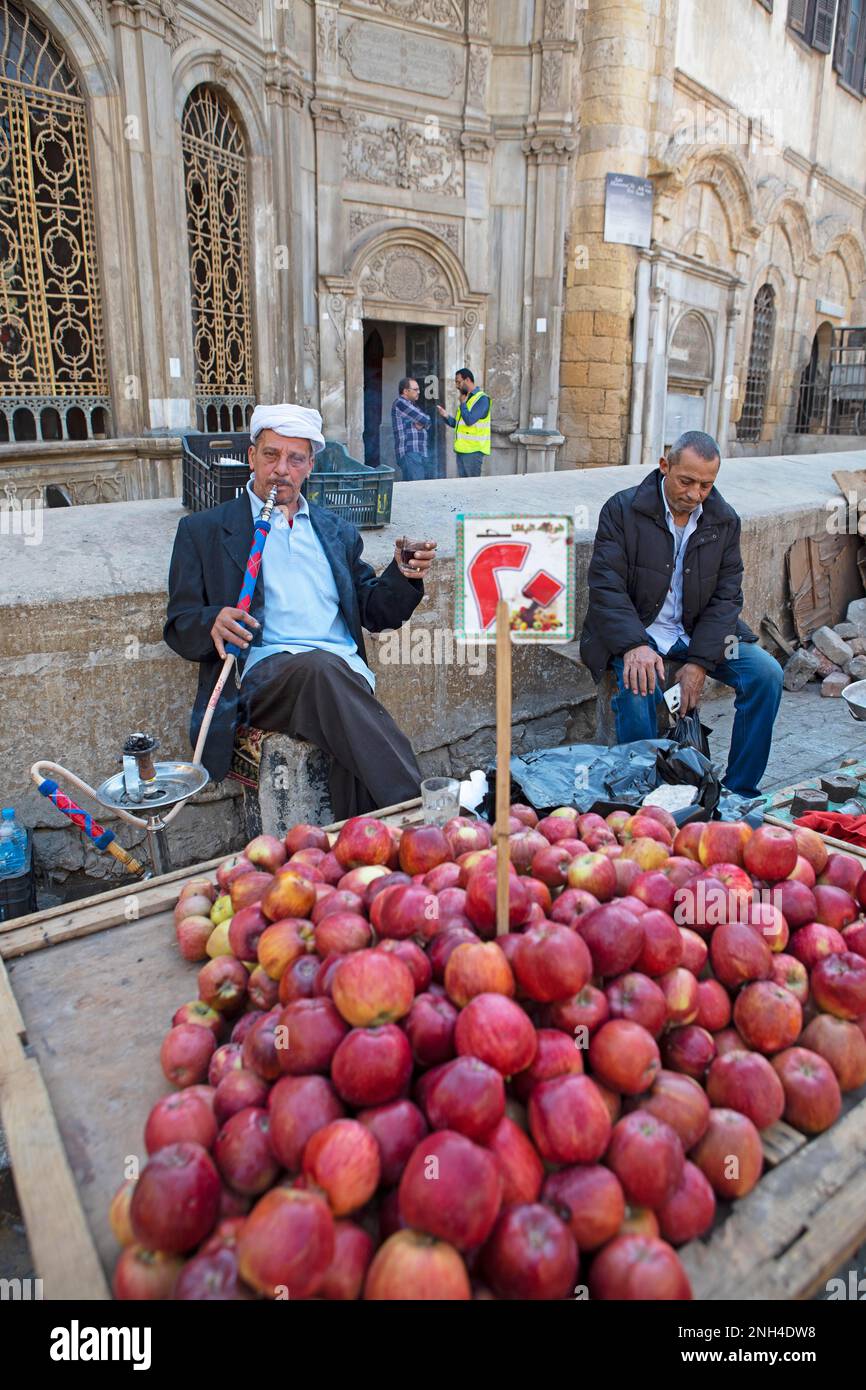 Uomo egiziano che fuma narghilè o narghilè in una bancarella di frutta, Città Vecchia, il Cairo, Egitto Foto Stock