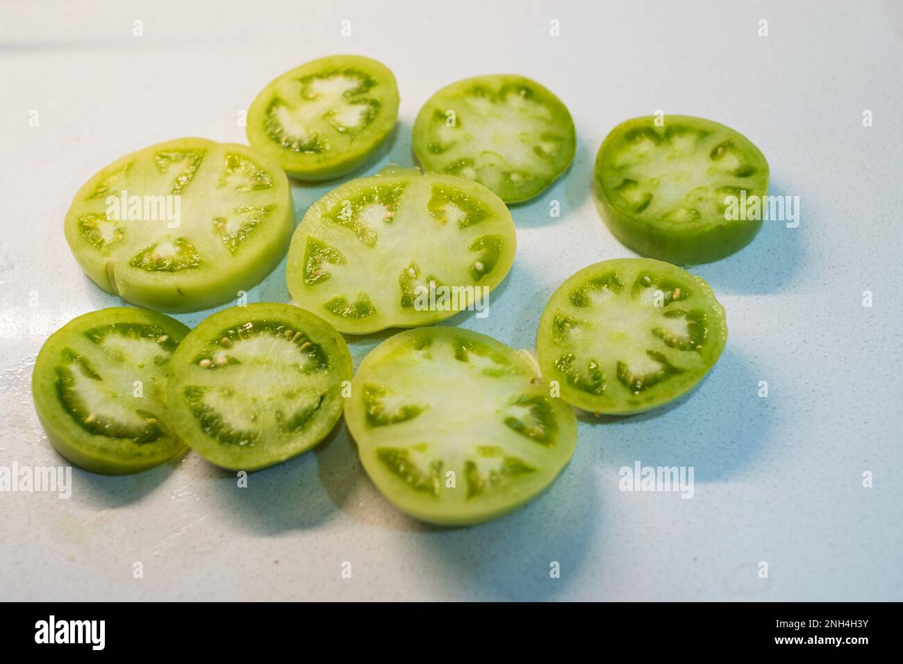 Fette di pomodoro fresco verde su sfondo bianco pronte per essere impanate e friggete. Kansas, Stati Uniti. Foto Stock