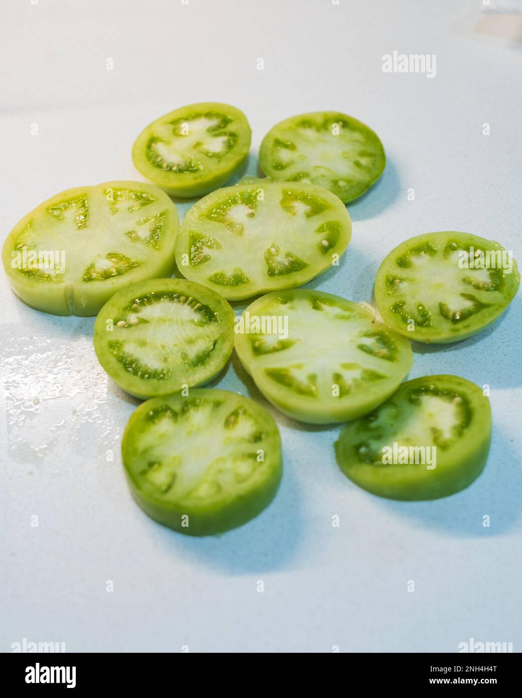 Pomodori verdi a fette pronti per la panatura e la frittura su fondo bianco . Foto Stock