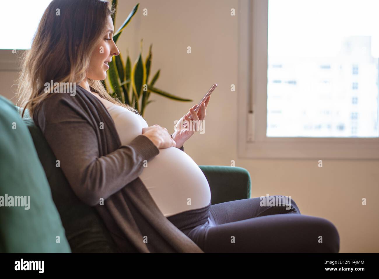 donna incinta che utilizza uno smartphone Foto Stock