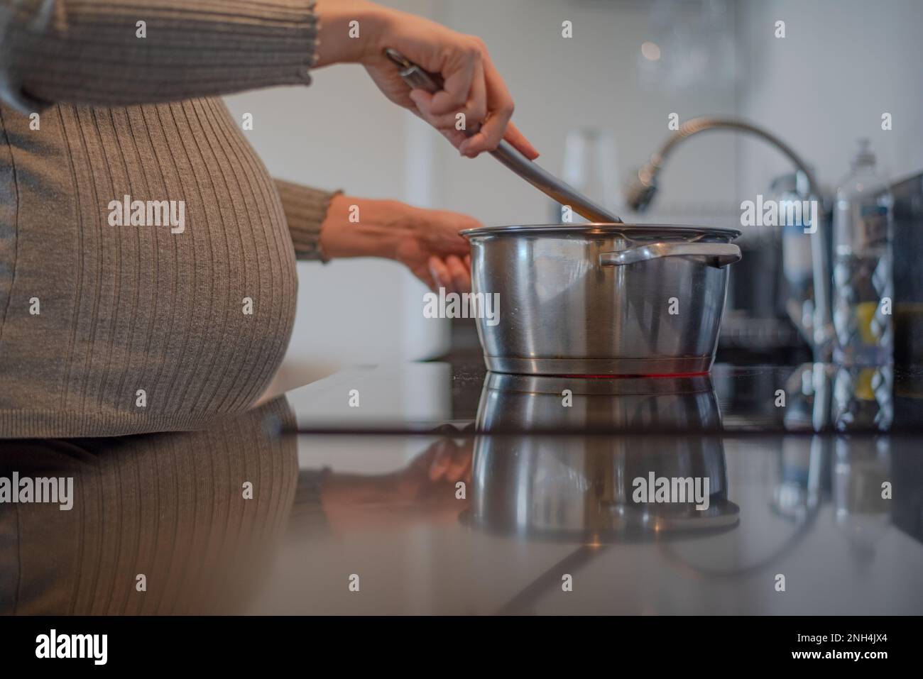 donna incinta che prepara pasti postpartum Foto Stock