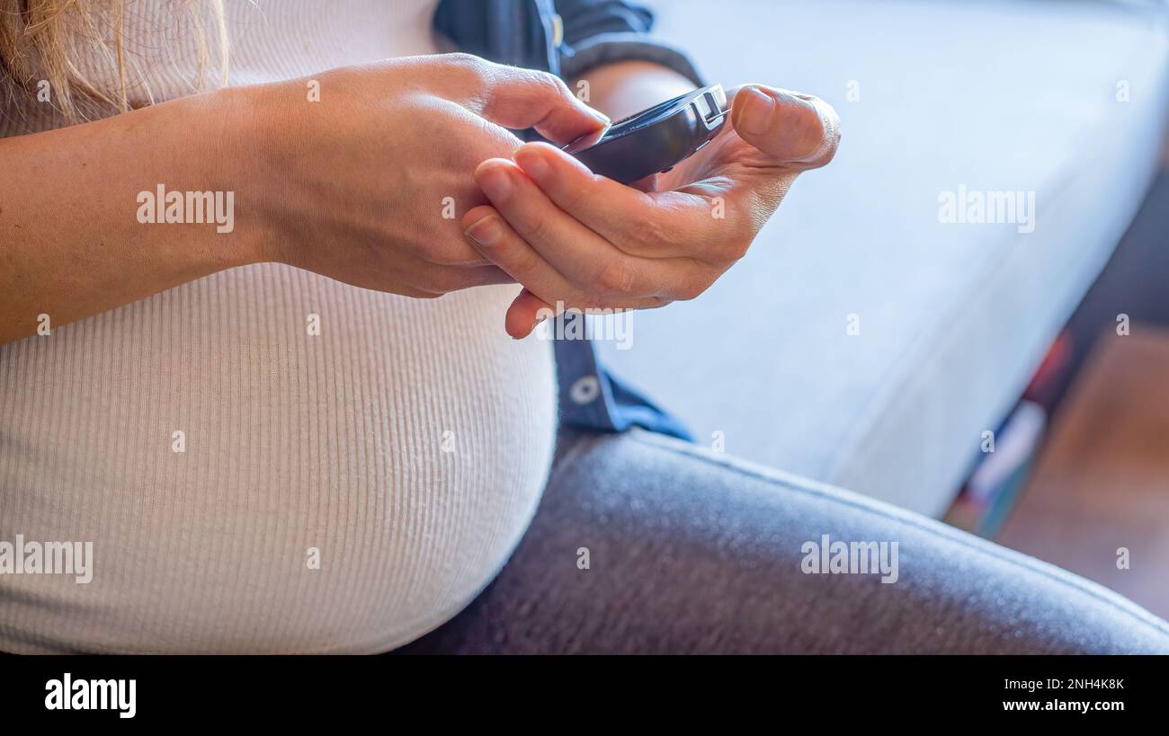 Primo piano della donna incinta che sta monitorando il suo glucosio nel sangue Foto Stock