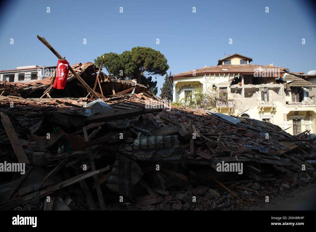 Una bandiera turca è issata sul relitto di un edificio nel centro storico di Antakya, distrutto dai potenti terremoti gemelli di Kahramanmaraş. Foto Stock