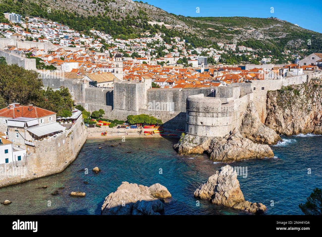 Spiaggia di sabbia alla Baia di Kolorina, con l'imponente Forte Bokar e i tetti di tegole rosse della città vecchia di Dubrovnik sulla costa dalmata della Croazia Foto Stock