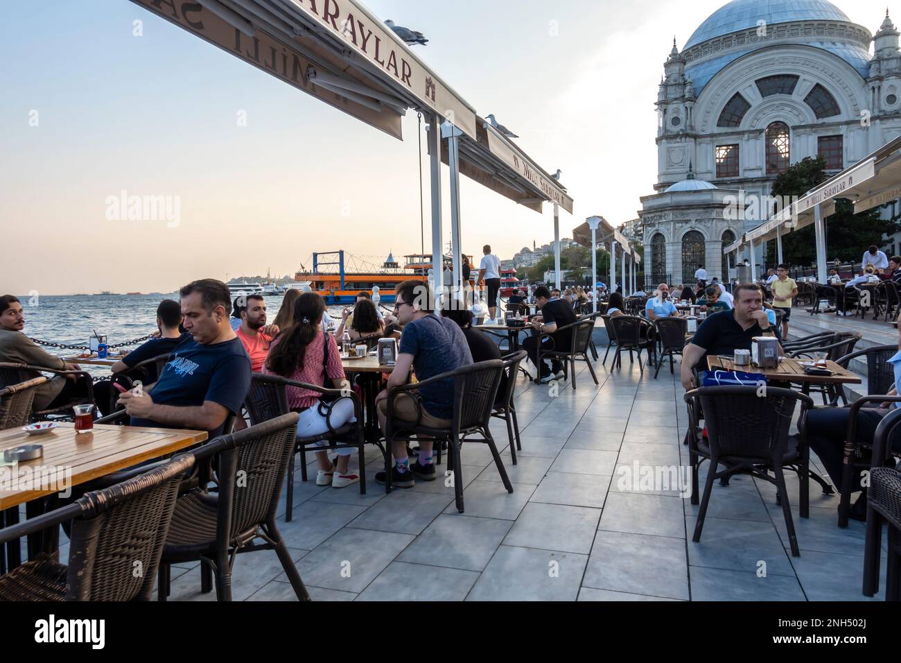 Dolmabahce Cafe Besiktas, Istanbul Türkiye. Vista sul Bosforo. Gente turisti al caffè all'aperto Istanbul Foto Stock