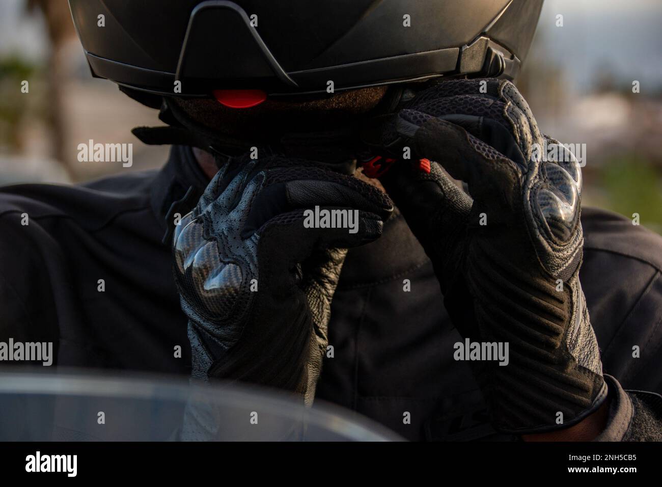 Primo piano dettaglio delle mani di un ciclista con guanti che indossa il casco. Concetto di sicurezza stradale Foto Stock