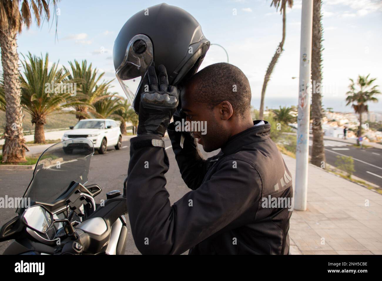 Sorridente ciclista afro-americana indossando il casco integrale. Concetto di sicurezza stradale Foto Stock